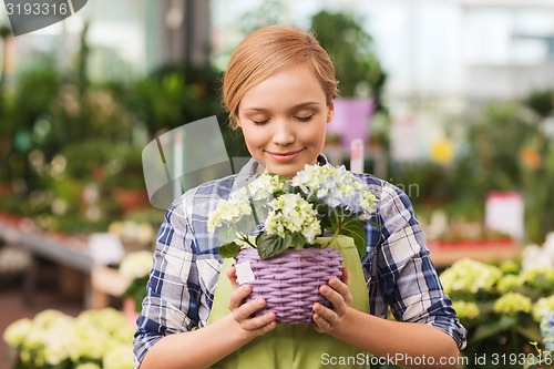 Image of happy woman smelling flowers in greenhouse