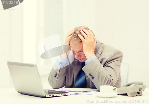 Image of upset older businessman with laptop and telephone