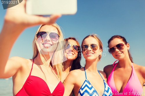 Image of group of smiling women making selfie on beach