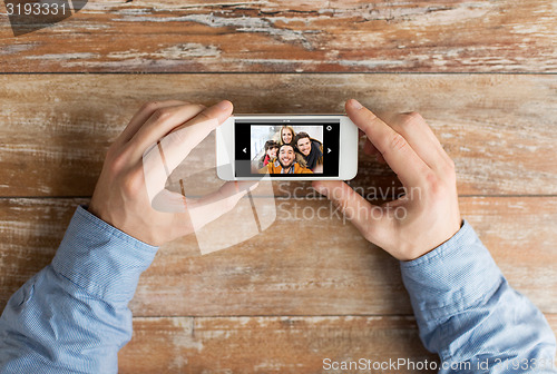 Image of close up of male hands with photo on smartphone