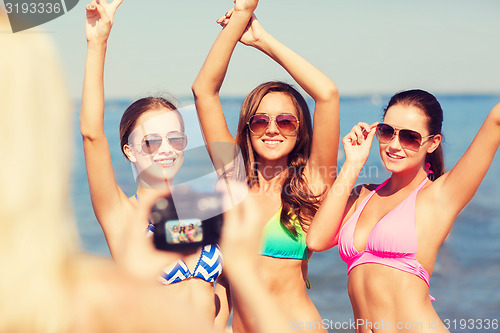 Image of group of smiling women photographing on beach