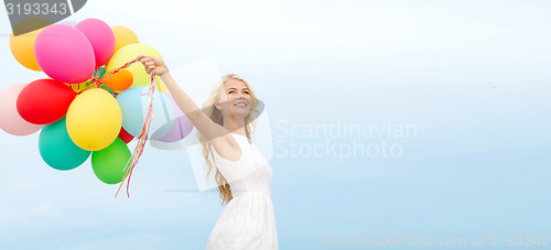 Image of smiling woman with colorful balloons outside