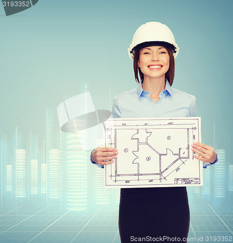 Image of smiling businesswoman in helmet showing blueprint