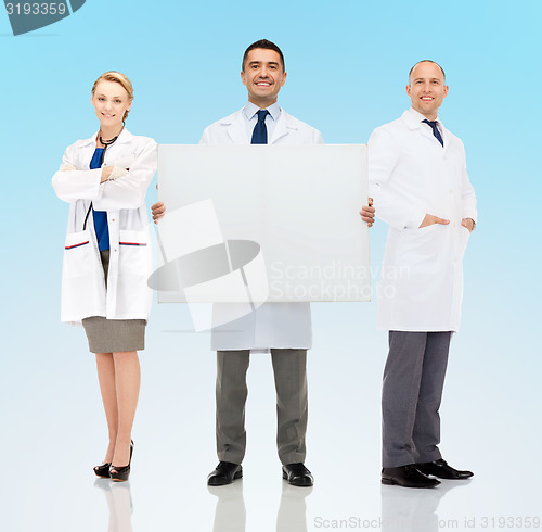 Image of group of smiling doctors holding white blank board