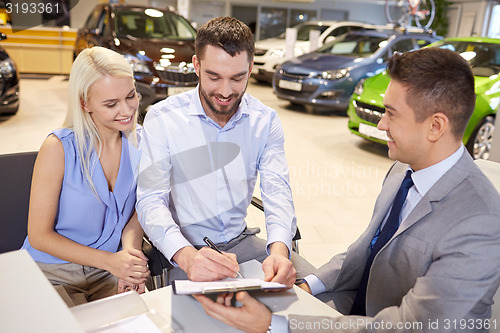 Image of happy couple with car dealer in auto show or salon