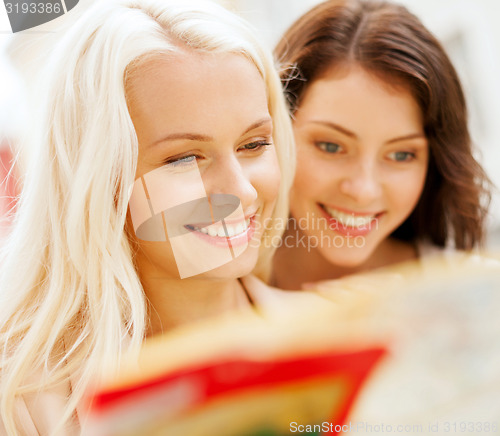 Image of beautiful girls looking into tourist map in city