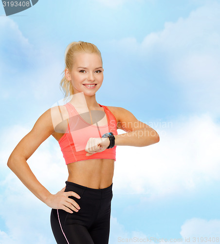 Image of smiling woman with heart rate monitor on hand