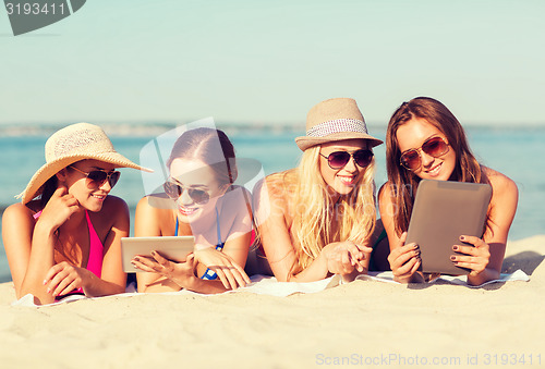 Image of group of smiling young women with tablets on beach