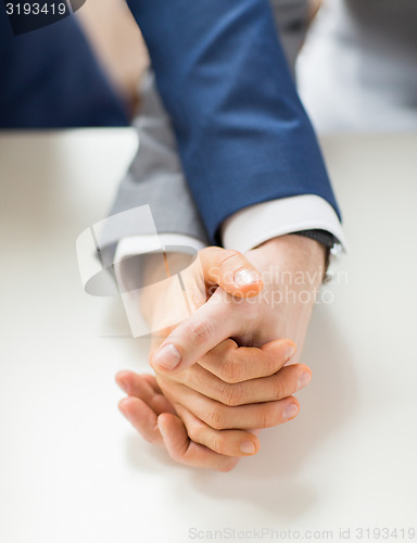 Image of close up of happy male gay couple holding hands