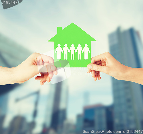 Image of man and woman hands with paper house