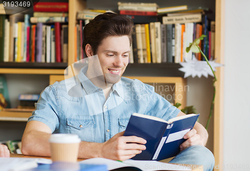 Image of happy student reading book and drinking coffee