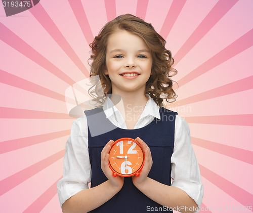 Image of happy girl with alarm clock over pink background