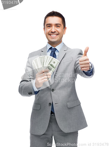 Image of smiling businessman with money showing thumbs up