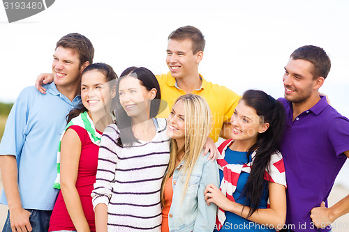 Image of group of happy friends hugging on beach