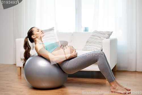 Image of happy pregnant woman exercising on fitball at home