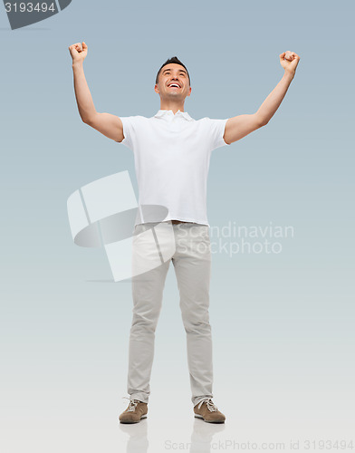 Image of happy man with raised hands over gray background