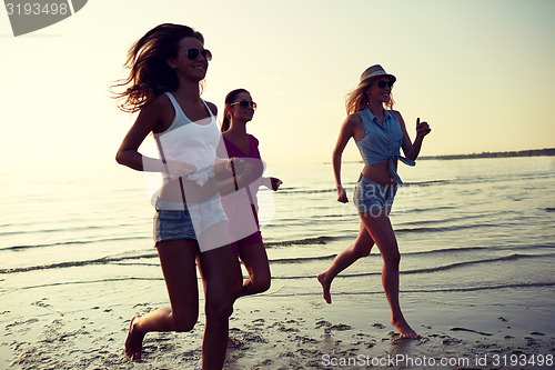 Image of group of smiling women running on beach
