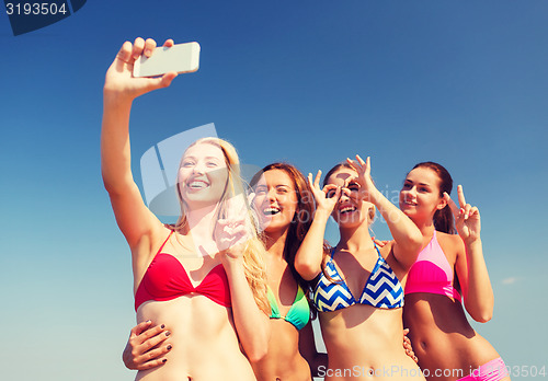 Image of group of smiling women making selfie on beach