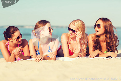 Image of group of smiling women in sunglasses on beach