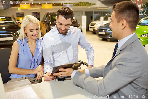 Image of happy couple with car dealer in auto show or salon