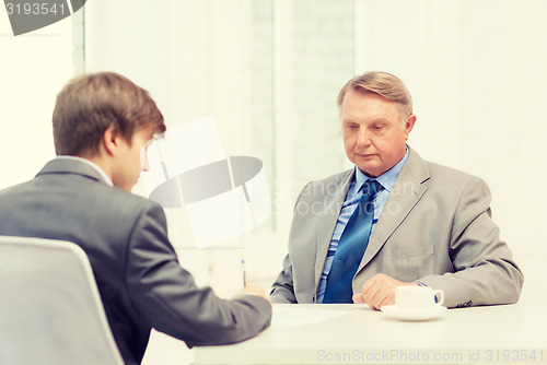 Image of older man and young man signing papers in office