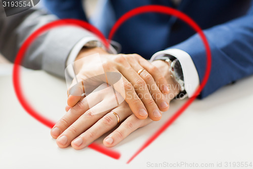 Image of close up of gay couple hands with wedding rings on