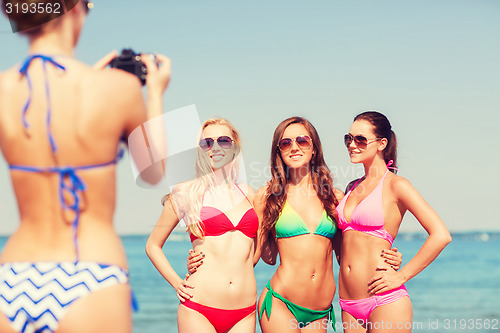 Image of group of smiling women photographing on beach