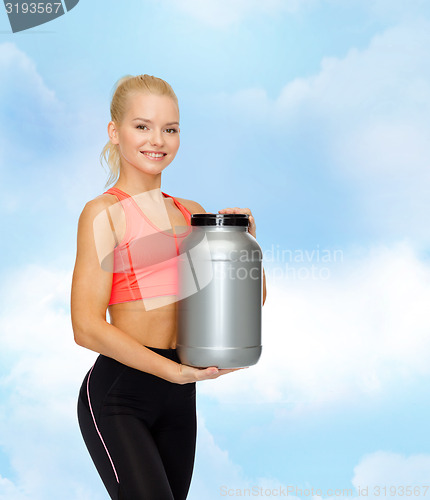 Image of smiling sporty woman with jar of protein