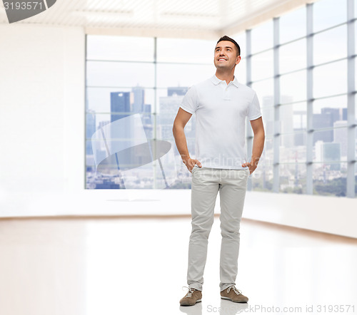 Image of smiling man with hands in pockets looking up