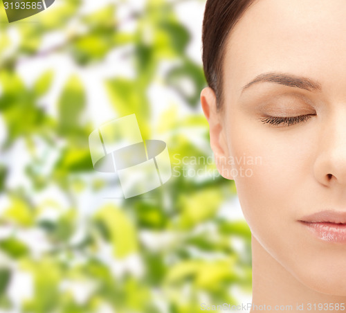 Image of young woman face over green leaves background