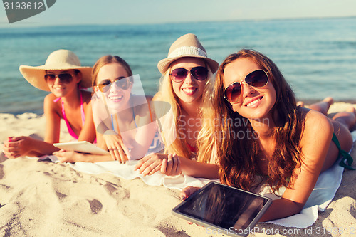 Image of group of smiling young women with tablets on beach