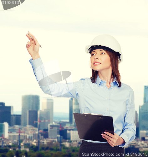 Image of smiling businesswoman in helmet with clipboard