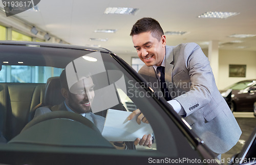 Image of happy man with car dealer in auto show or salon