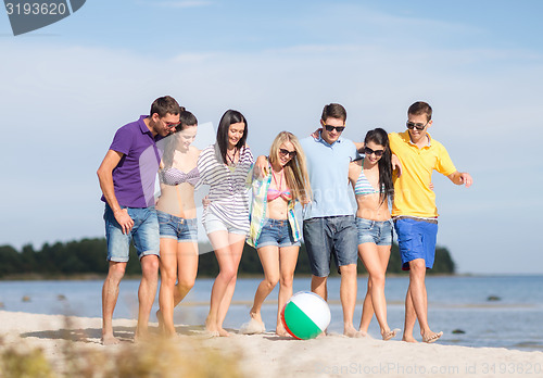 Image of group of happy friends walking along beach