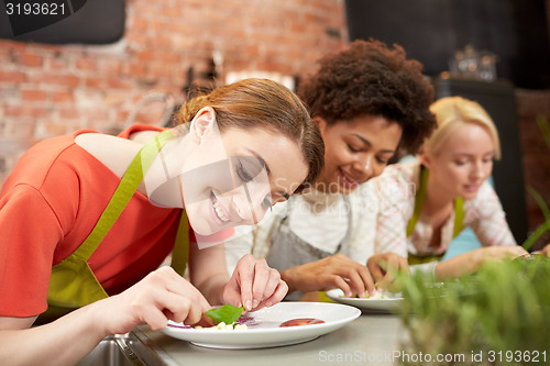 Image of happy women cooking and decorating dishes