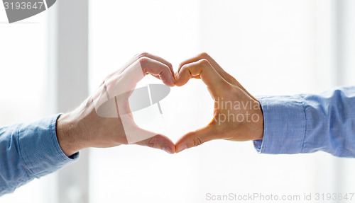 Image of close up of male gay couple hands showing heart