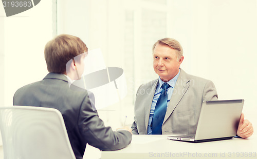 Image of older man and young man signing papers in office