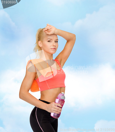 Image of tired sporty woman with towel and water bottle