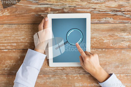 Image of close up of male hands with magnifier on tablet pc