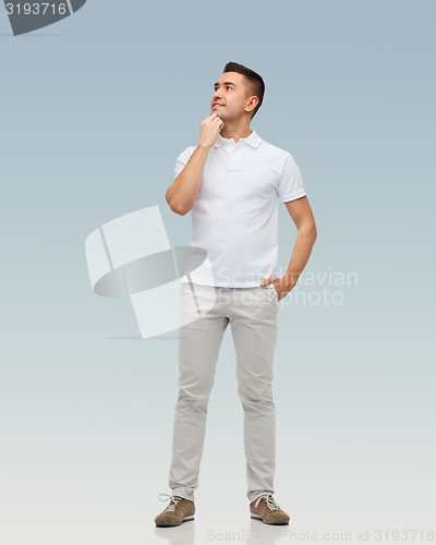 Image of smiling man with hands in pockets looking up