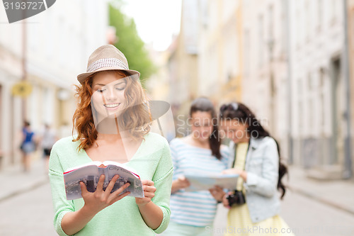 Image of smiling teenage girls with city guides and camera