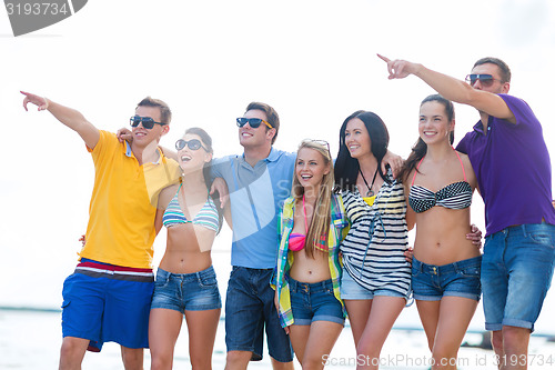 Image of group of happy friends walking along beach