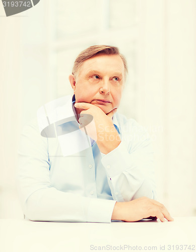 Image of stressed old man holding head at home