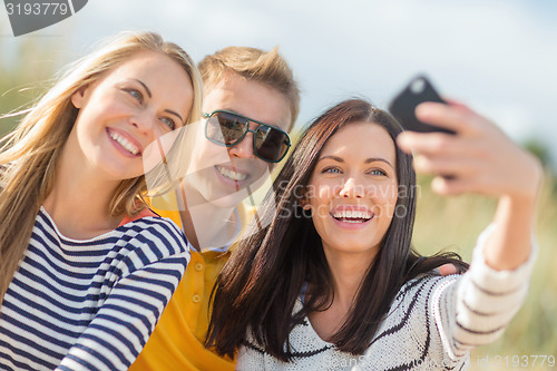 Image of group of friends taking selfie with cell phone