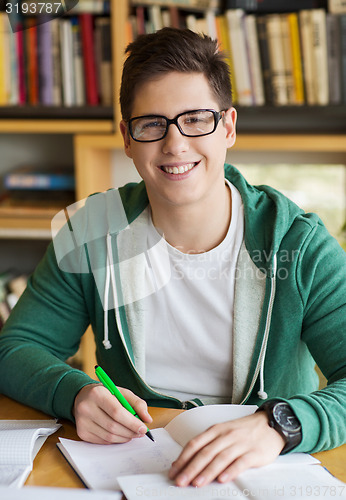 Image of happy student writing to notebook in library