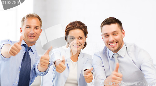 Image of business team showing thumbs up in office