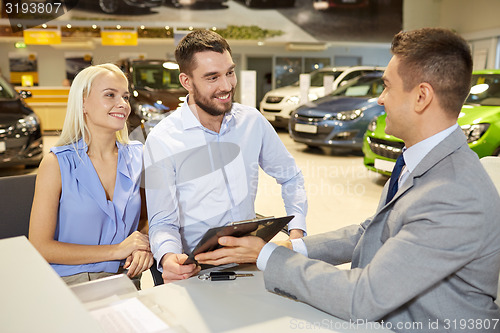 Image of happy couple with car dealer in auto show or salon