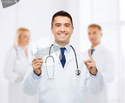 Image of smiling male doctor in white coat with tablets