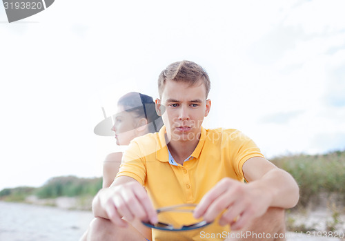 Image of unhappy couple sitting on beach