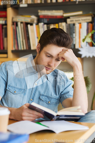 Image of male student reading book in library